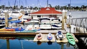 A marina with various boats docked, a small building with a red roof, and a clear view of the water.