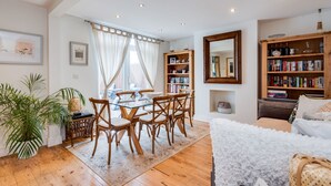 A living room with a dining area, a bookshelf, and a large mirror. - Headington Orchard - 3 Bedroom House & parking & garden (Oxford)