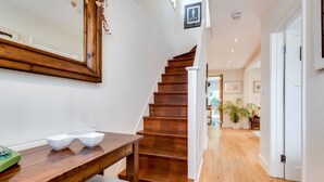 A wooden staircase with white railings, a wooden table with bowls, and a mirror on the wall. - Headington Orchard - 3 Bedroom House & parking & garden (Oxford)