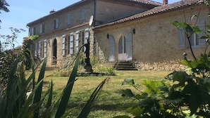 A two-story stone building with arched windows and a tiled roof.