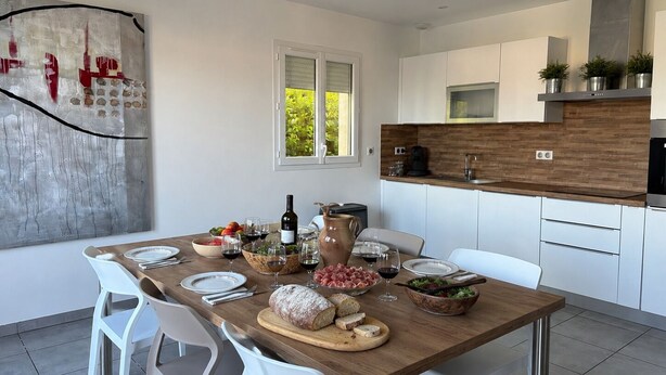 Une cuisine moderne avec des armoires blanches, un plan de travail en bois et une grande fenêtre.