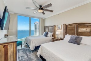 Relax in this stylish room with two beds, a flat-screen TV, and a ceiling fan, offering a view of a nearby building and water.