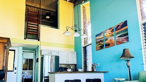 Een ruime woonkamer met een keukeneiland, een plafondventilator en een eethoek.