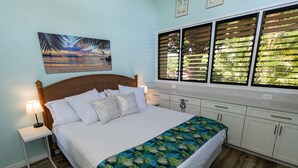 Een slaapkamer met een bed, nachtkastjes, een raam met jaloezieën en een schilderij aan de muur.
