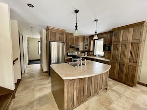 A kitchen with wooden cabinets, a stainless steel refrigerator, a built-in island with a sink, and pendant lighting. - Le Rivat – Chalet for 12 guests + 2 children (Saint-Gabriel-de-Valcartier)