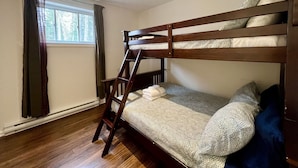 Ein Stockbett mit einer Leiter, ein Fenster mit Vorhängen und ein Holzboden.