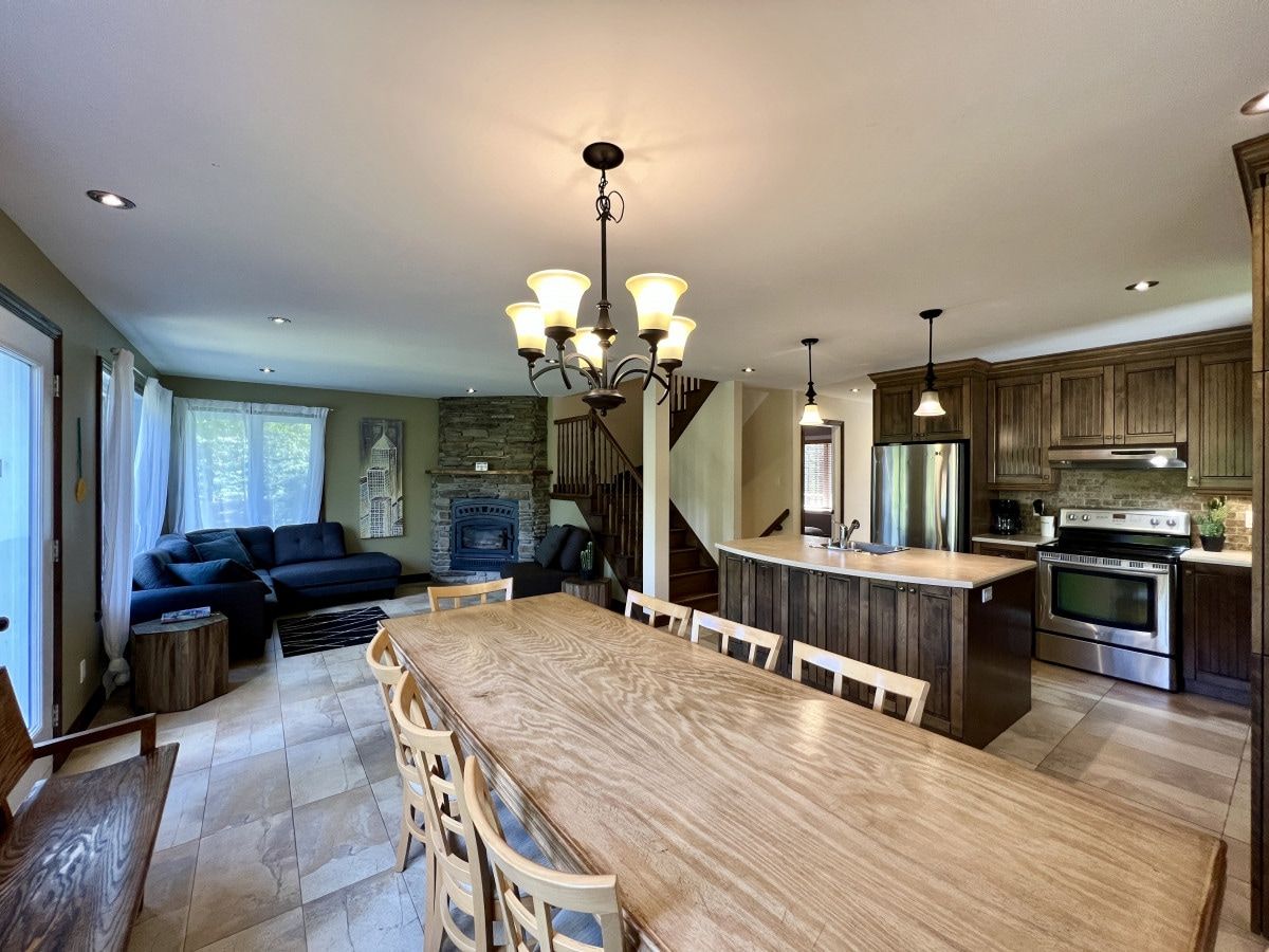 A spacious kitchen with a central island, wooden dining table, and modern appliances.