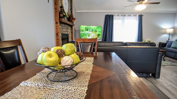 A dining area with a wooden table, a woven placemat, and a bowl of green apples. - Beautiful, spacious, clean house for families #1 (Overland Park)