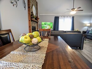 A dining area with a wooden table, a woven placemat, and a bowl of green apples. - Beautiful, spacious, clean house for families #1 (Overland Park)