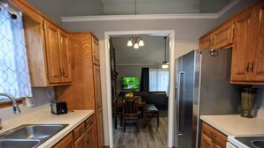 A kitchen with wooden cabinets, stainless steel appliances, and a dining area with a TV. - Beautiful, spacious, clean house for families #1 (Overland Park)