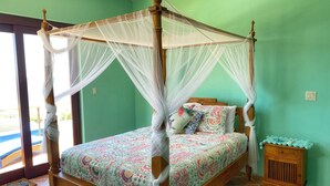 Een hemelbed met een kleurrijk patroonbed, een houten nachtkastje met een blauw decoratief object en een betegelde vloer.