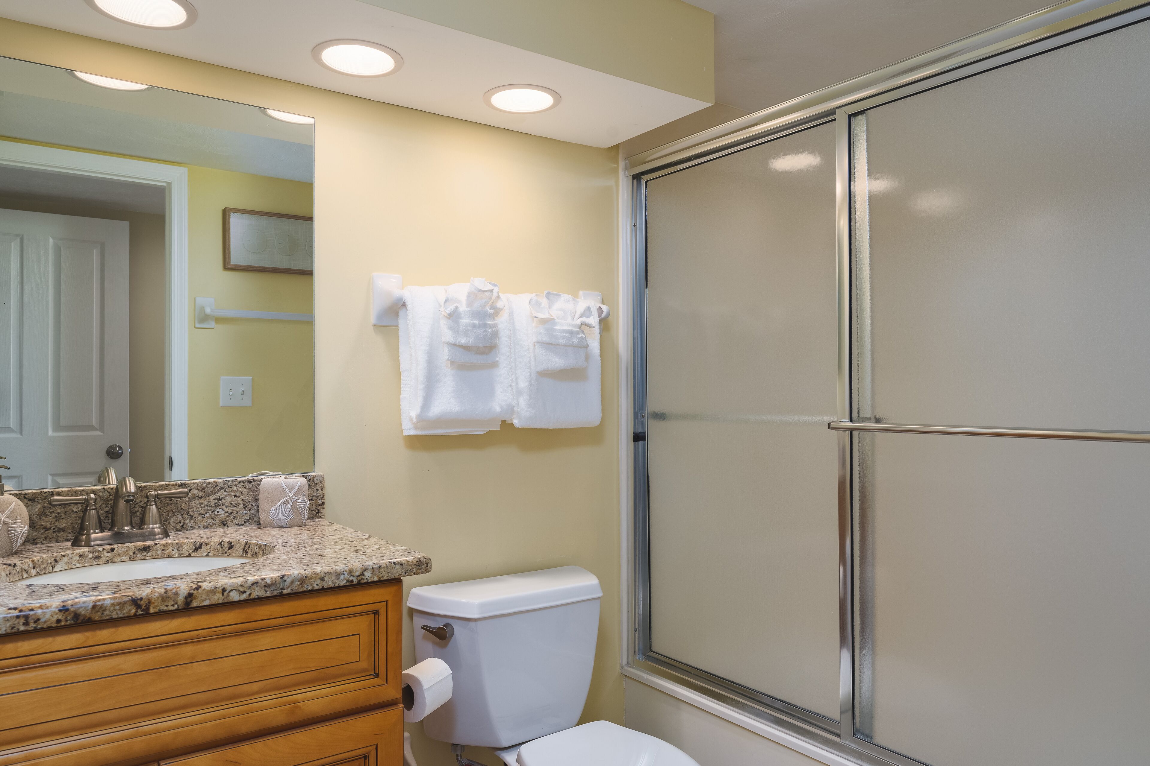 Baño con lavamanos de encimera de granito, inodoro y cabina de ducha.