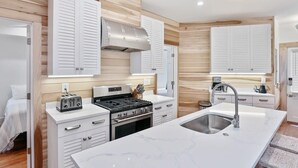 Una cocina moderna con armarios blancos, estufa integrada y una isla grande con lavamanos.