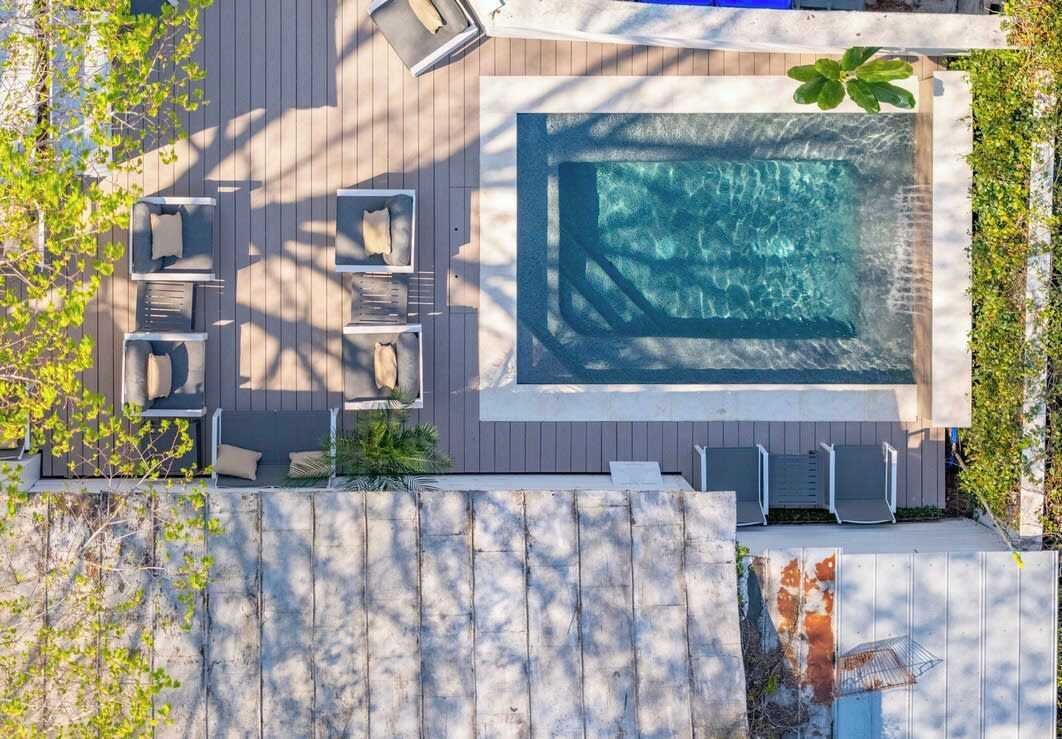 En vy från ovan av ett däck med en swimmingpool, solstolar och ett trästaket.