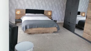 A modern bedroom with a large bed, two bedside tables, a mirror, and a wardrobe. - House with 5 Double bedrooms including large family room,4 Bathrooms, Gym &patio (Brough)