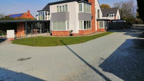 A modern two-story house with a covered patio and a gravel driveway. - House with 5 Double bedrooms including large family room,4 Bathrooms, Gym &patio (Brough)