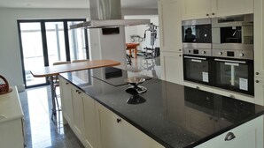 A modern kitchen with a black countertop, stainless steel appliances, and a large window providing natural light. - House with 5 Double bedrooms including large family room,4 Bathrooms, Gym &patio (Brough)