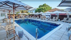 Piscina aquecida com estilo de resort, espreguiçadeiras e guarda-sóis.