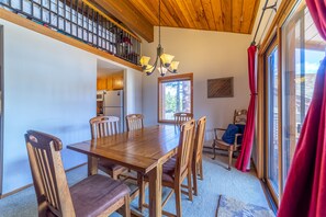 Enjoy meals in this dining area with a large table and six chairs, surrounded by a high ceiling and a large window with an outdoor view.