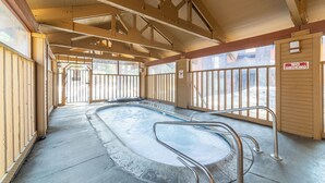 En inomhuspool med träbjälkar, en skylt som förbjuder rökning och utsikt över utomhusområdet.