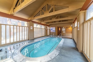 Swim laps in the pool surrounded by a rustic wooden ceiling and glass barrier.