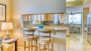 Une cuisine dotée d’un îlot central, de tabourets de bar, d’une décoration en forme d’étoile de mer et donnant sur la salle à manger.
