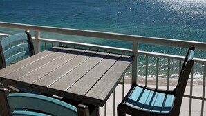 Un balcon avec une table et des chaises donnant sur l’océan.