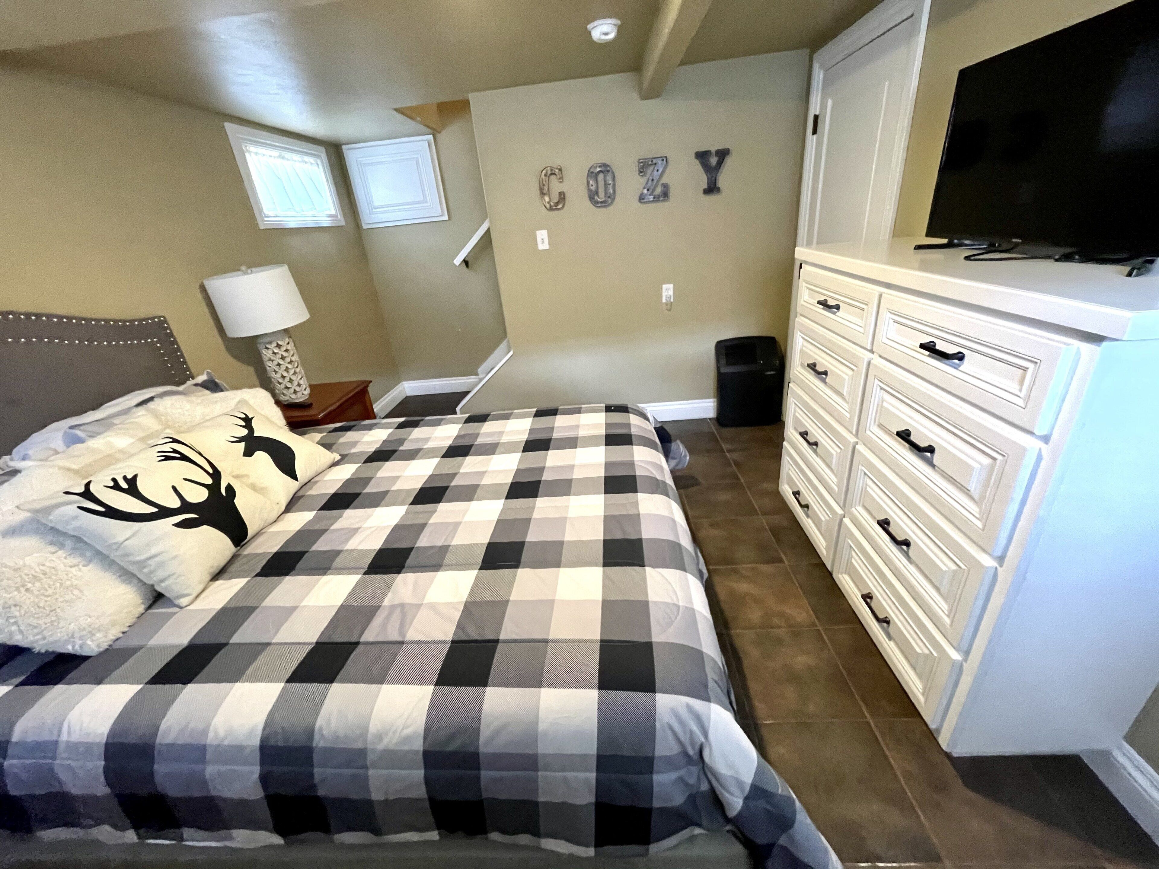 A bedroom with a bed, dresser, TV, and wall decorations.