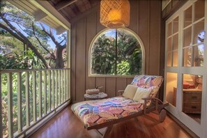 Enjoy a peaceful retreat on the balcony with a view of lush greenery, featuring a comfortable bench and a small table.