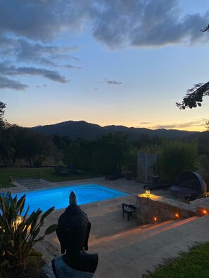 A serene outdoor setting with a swimming pool, a Buddha statue, and a stone bench. - Beautiful air-conditioned villa with jacuzzi pool, large, quiet property with trees. (20226 BELGODERE)