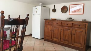 Een keuken met een witte koelkast, houten kastjes en een eettafel met een stoel.