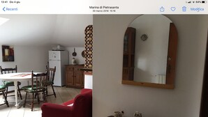Een eetgedeelte met een ronde tafel, stoelen, een rode bank en een houten kast.