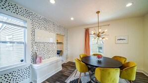 A dining area with a round table, yellow chairs, a modern chandelier, and a patterned wall. - Tremont! 7 min to downtown Cle (Cleveland)