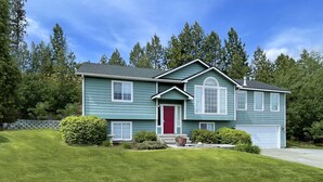 A two-story house with a red door, a garage, and a well-maintained lawn. - Blackhawk 5BD Home: Hot Tub, Arcade, near Whitworth & Green Bluff (Spokane)