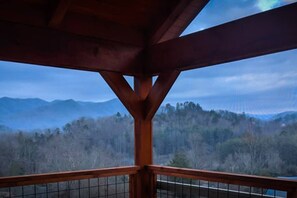 Un balcon en bois offrant une vue sur une chaîne de montagnes boisée.