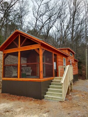 Une cabane dotée d’une grande façade vitrée, d’un escalier en bois et d’un toit en pente.