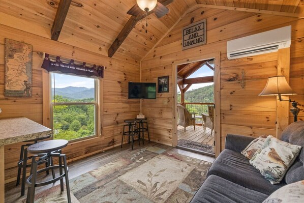 Une cabane en bois comprenant un coin repas, un canapé, une télévision et une pancarte sur laquelle on peut lire : « DÉTENDEZ-VOUS ET RELÂCHEZ-VOUS ».