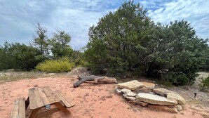 Ein Picknicktisch in einer natürlichen Umgebung mit Bäumen und Steinen.