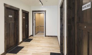 Un pasillo de hotel con puertas de madera, un cartel que indica la Suite 202 y suelo cubierto de alfombra.