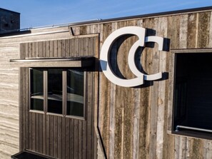 Een gebouw met een groot 'C'-bord aan de zijkant, houten bekleding en een raam.