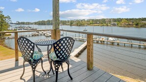 A wooden deck with two chairs and a table, overlooking a calm lake with boats and a dock. - Waterfront Views & Boat Slip, Blackwell Point #B (Oriental)