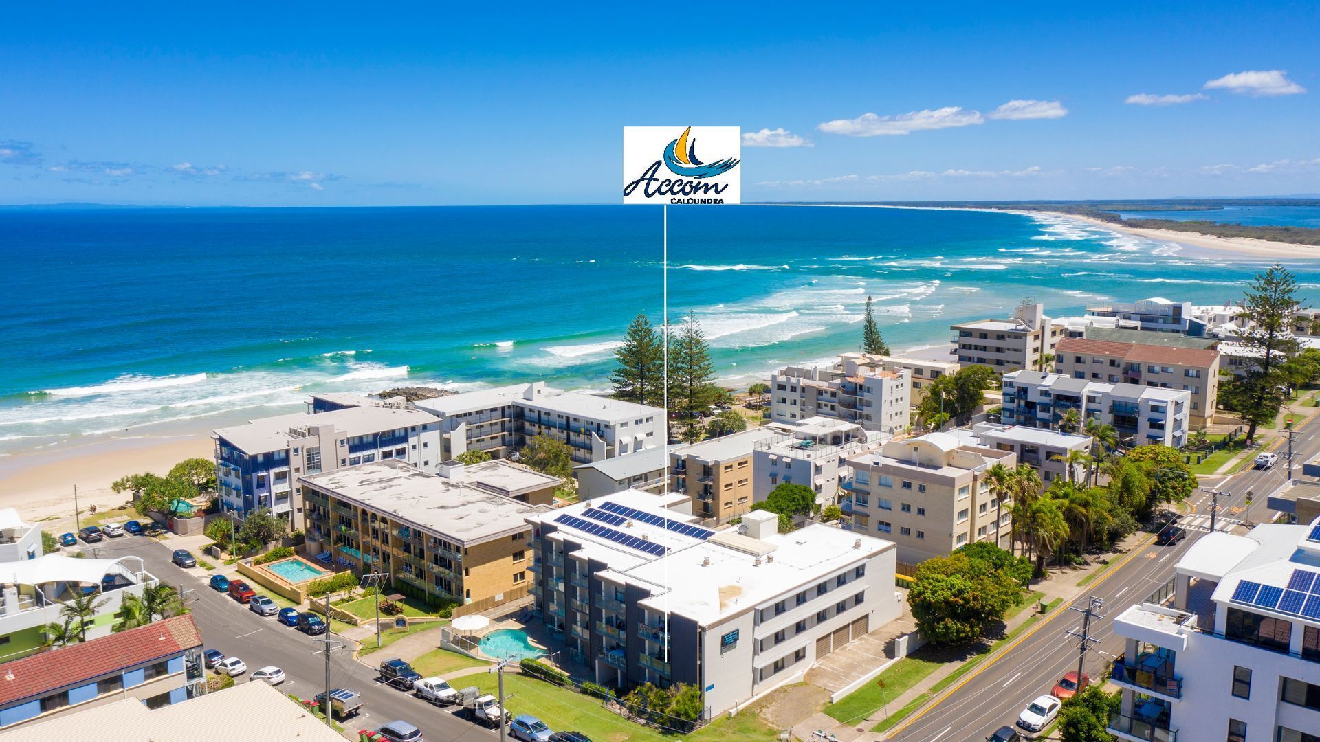 A coastal hotel with multiple buildings, a swimming pool, and a view of the ocean.