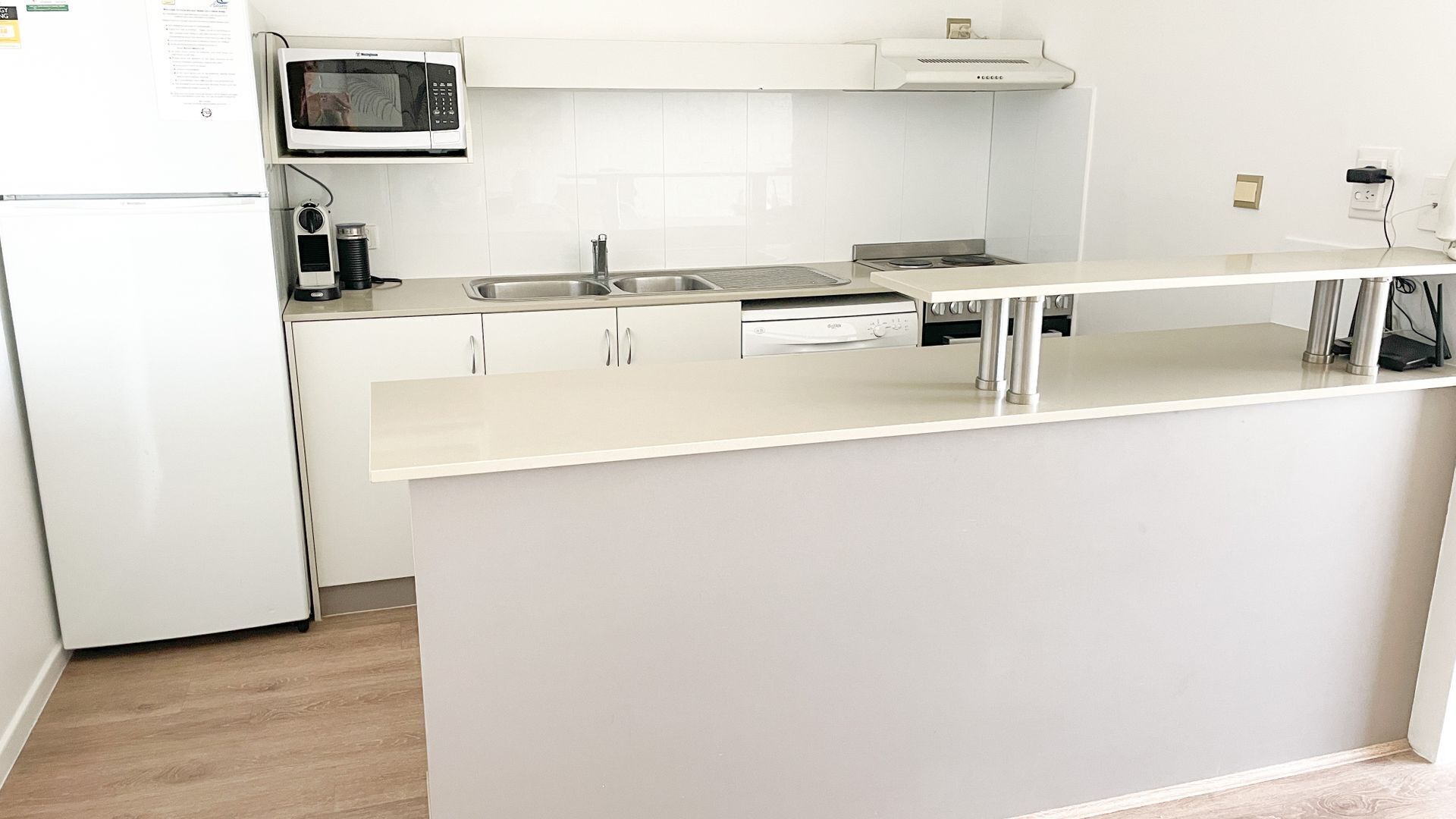 Eine moderne Küche mit weißen Schränken, einer Edelstahl-Spüle, einer Mikrowelle und einem eingebauten Backofen.
