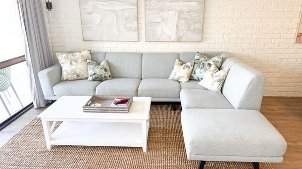 A living room with a grey sectional sofa, a white coffee table, and two abstract paintings on the wall.