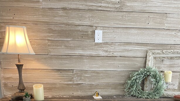 Un caminetto in pietra con mensola, una candela, una piccola pianta e una ghirlanda decorativa.