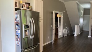 Una cucina moderna con frigorifero in acciaio inossidabile, mobili bianchi e pavimento in legno.