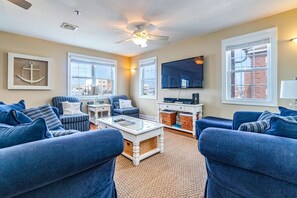 A living room with blue sofas, a coffee table, a TV, and a ceiling fan.