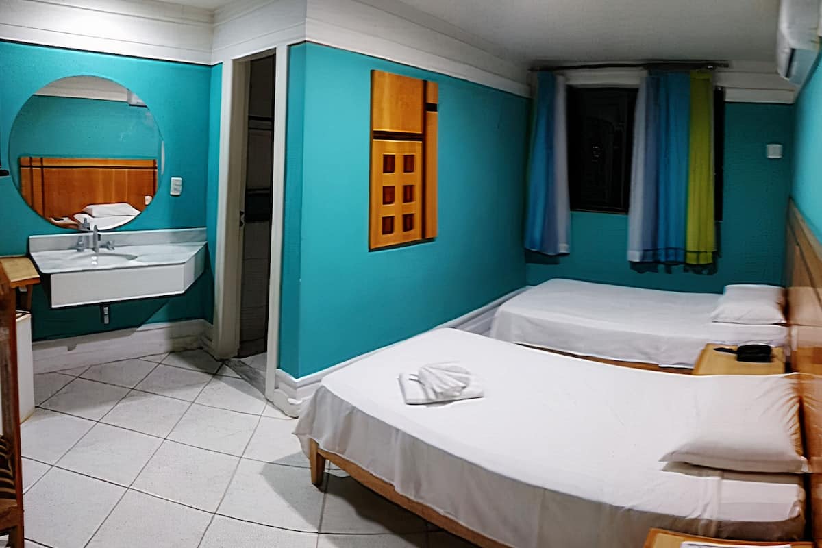Quarto com duas camas, pia e espelho.