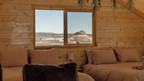 Una cabaña de madera con un ventanal grande que da a un paisaje rocoso.