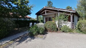 Een klein huis met een grindpad, omringd door groen en bomen.
